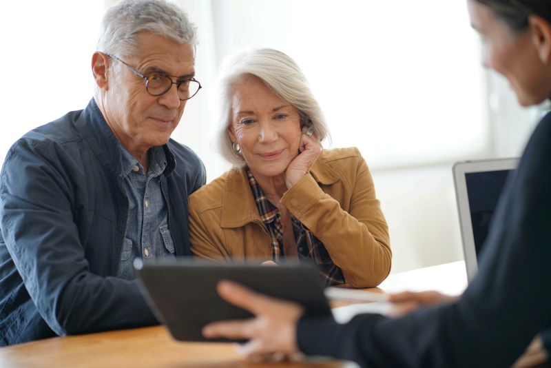 high net worth senior couple looking at tablet with financial advisor